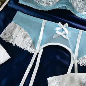 Détail d'un porte-jarretelles en dentelle bleu clair avec nœuds blancs sur soie bleue