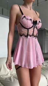 Détail de nuisette en résille rose avec broderie florale noire et nœuds décoratifs