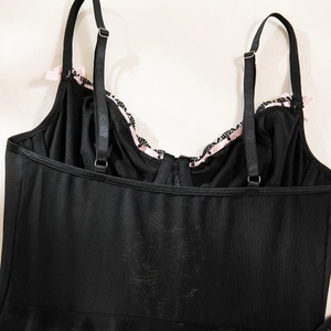 Detail of black mesh lingerie with pink lace trim and satin bows on adjustable straps