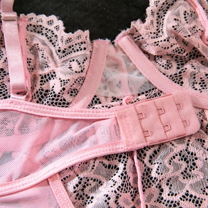 Detail of pink floral lace bodysuit back with three-row hook closure and adjustable straps