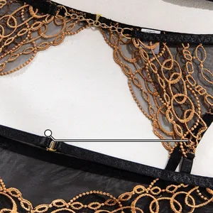 Detail of sheer black mesh with gold embroidery and metal chains on lingerie set