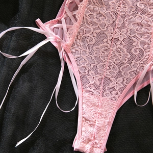 Close-up of pink floral lace bodysuit featuring satin cross-strap lace-up side details