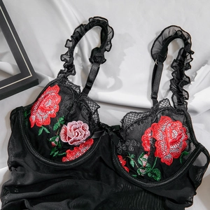 Detailed close-up of rose embroidery on black lace bodysuit with ruffled shoulder straps