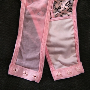 Detailed macro view of pink lace bodysuit bottom with snap button closure and mesh fabric