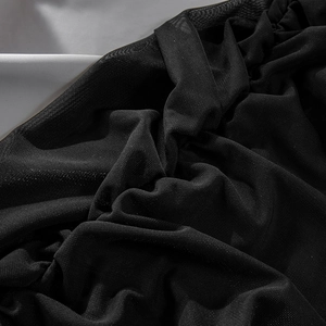 Macro detail of sheer black lace and mesh fabric showing delicate floral embroidery texture
