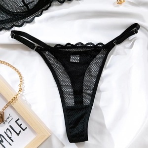 Détail d'un string en dentelle noire à bretelles réglables sur fond de soie blanche