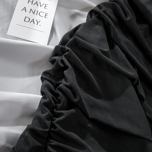 Close-up of black mesh fabric with detailed ruching and fine net texture on dress