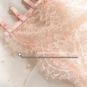 Close-up of pink transparent floral lace fabric with adjustable straps and metal buckles
