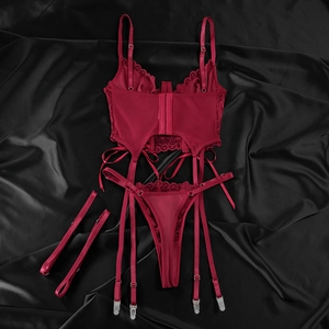 Detail view of dark red lace corset set with garter straps on black silk background