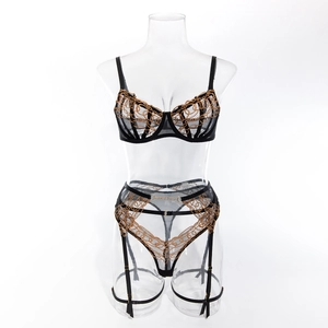 Detailed view of sexy black mesh lingerie set with gold embroidery and garter belt