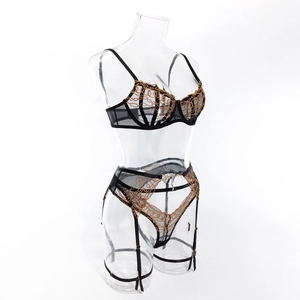 Detail of black mesh lingerie with gold chain embroidery and garter belt hooks