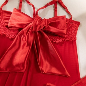 Detail of red sexy lingerie showing large satin bow decoration and lace trim on sheer mesh