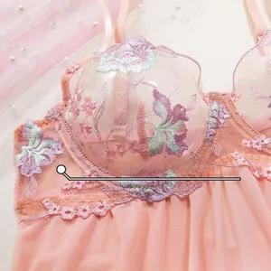 Detail of pink mesh bodysuit featuring delicate floral embroidery and scalloped lace trim