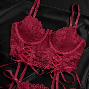 Close-up of deep red lace corset lingerie with ribbon lace-up detail and floral texture