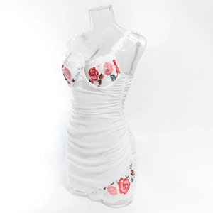 Close-up of white ruched mini dress with red rose embroidery and lace trim details