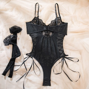 Close-up of black lace bodysuit with ribbon lacing and matching stockings on tulle