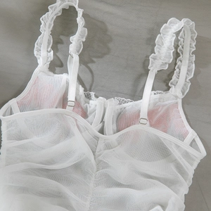 Detail of white lace ruffle straps and sheer mesh fabric with adjustable metal rings