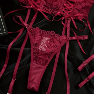 Detail view of burgundy lace thong with intricate crisscross straps and metal hardware