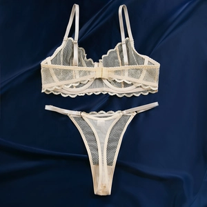 Détail de l'ensemble de lingerie en dentelle champagne sur fond de satin bleu foncé