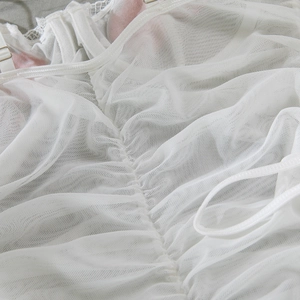 Close-up of white sheer mesh fabric with pleated texture and delicate lace edge