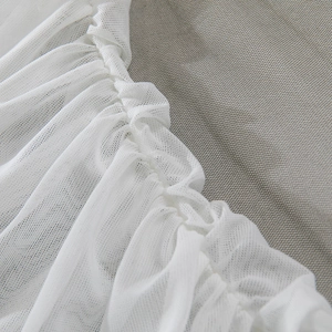Detail of white semi-transparent mesh fabric with elegant ruched texture and soft folds