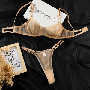 Dettaglio flat lay del set lingerie in rete color champagne con anelli metallici