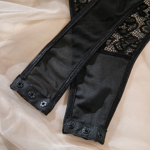 Close-up of black lace bodysuit featuring floral embroidery and metal snap closures