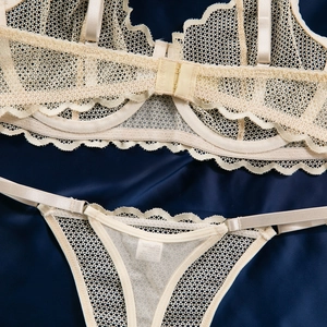 Détails d'un ensemble de lingerie en dentelle beige et résille sur satin bleu soyeux