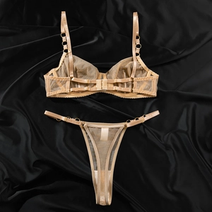 Dettaglio del set di lingerie in rete color champagne con anelli in metallo dorato