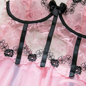 Détail d'une robe en tulle rose avec broderies florales et petit nœud en satin noir