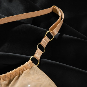Dettagli delle spalline regolabili con anelli dorati su lingerie in pizzo beige