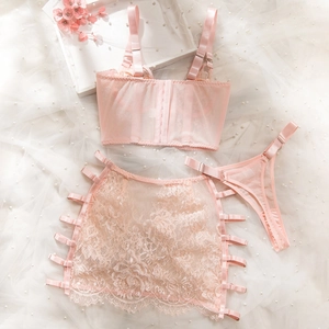 Detailed flat lay of pink lace lingerie three-piece set with mesh skirt and metal buckles