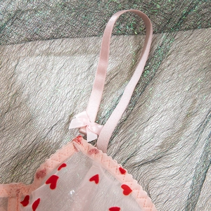 Détail de body en tulle rose avec flocage de coeurs rouges et nœuds délicats
