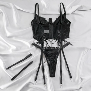 Flat lay of black lace lingerie set with corset, thong, and garter straps on white silk