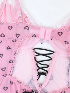 Dettaglio body in mesh rosa con stampa a cuore, pizzo bianco e lacci neri incrociati
