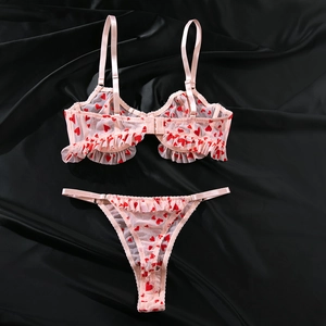 Détail de l'ensemble soutien-gorge et string en mesh rose avec motifs cœurs rouges