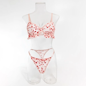 Détail d'un ensemble de lingerie rose clair avec motifs coeurs rouges et tulle plissé