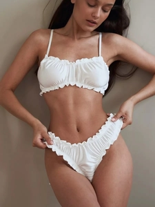 Detailed close-up of white satin lingerie set with elegant ruffle trim and gathered texture