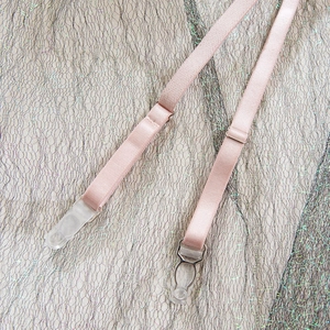 Gros plan d'un porte-jarretelles élastique rose avec boucles sur fond en résille