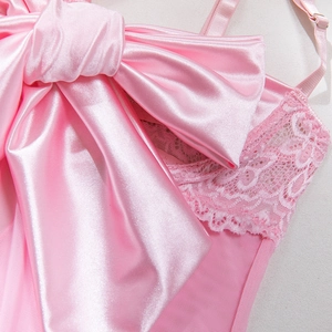 Detail of pink satin sleepwear featuring floral lace trim and a large decorative bow