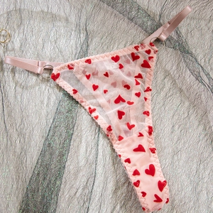 Détail du string en tulle rose avec coeurs rouges floqués et anneaux métalliques réglables