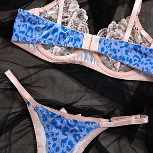 Flat lay of blue leopard print lingerie set with pink lace details on dark mesh background