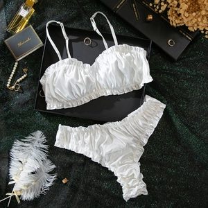 Detail of white satin lingerie set with pleated texture and pearl accessories