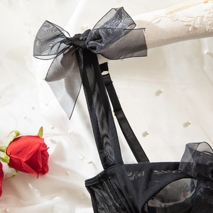 Detailed close-up of a black mesh corset featuring elegant organza bow straps on a hanger