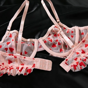 Détail de soutien-gorge en résille rose avec motifs cœurs rouges et bords à volants