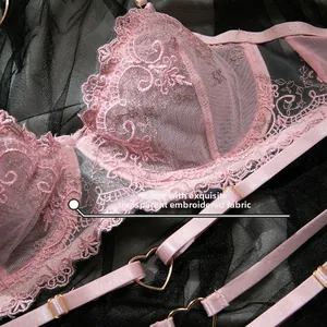 Détail de la broderie en dentelle rose avec boucle en métal en cœur et bretelles réglables
