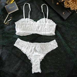 Detail of white ruffled lingerie set with lettuce trim and pleated texture on silk fabric
