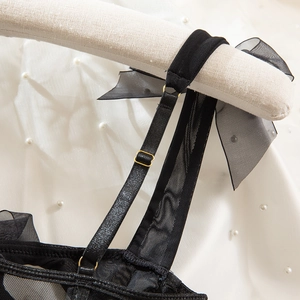 Detail of adjustable black mesh straps with gold metal buckles and organza bows