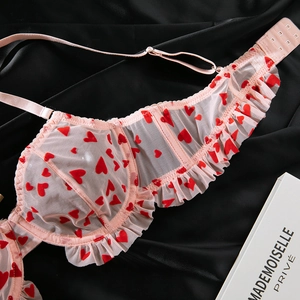Détail d'un soutien-gorge en résille rose avec motifs cœurs et volants délicats