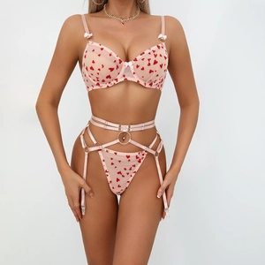 Détail d'un ensemble de lingerie en résille rose avec des cœurs rouges floqués